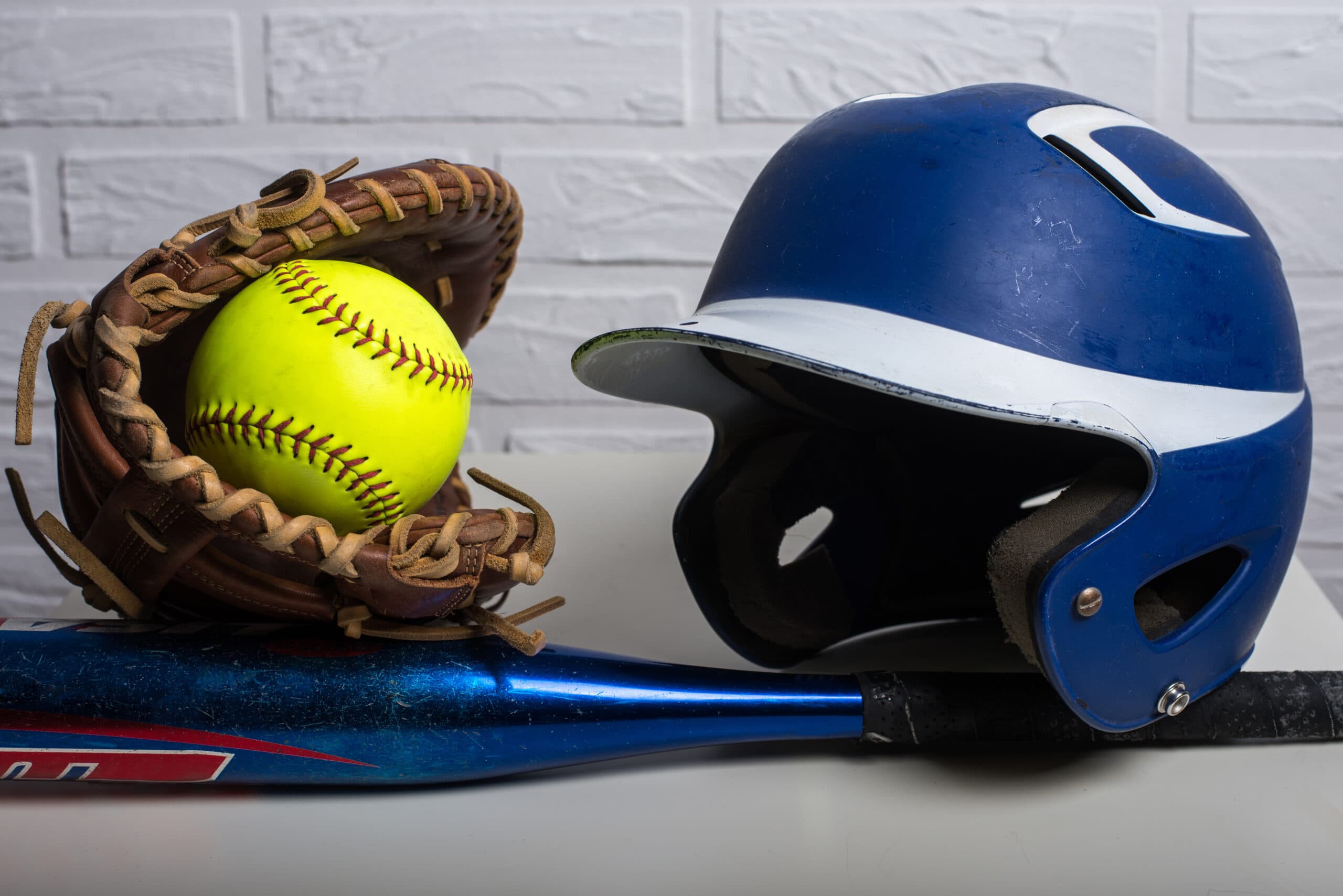 softball equipment, softball, helmet, glove and bat.